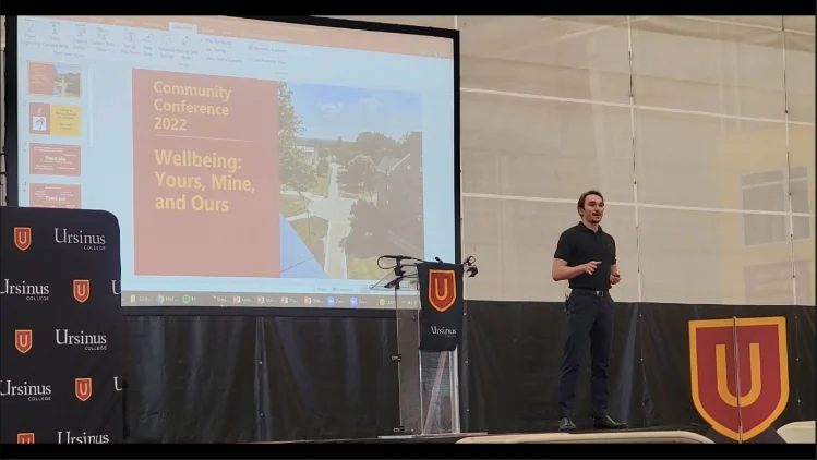 Evan presenting beside an Ursinus College banner